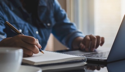 Hand taking notes at laptop